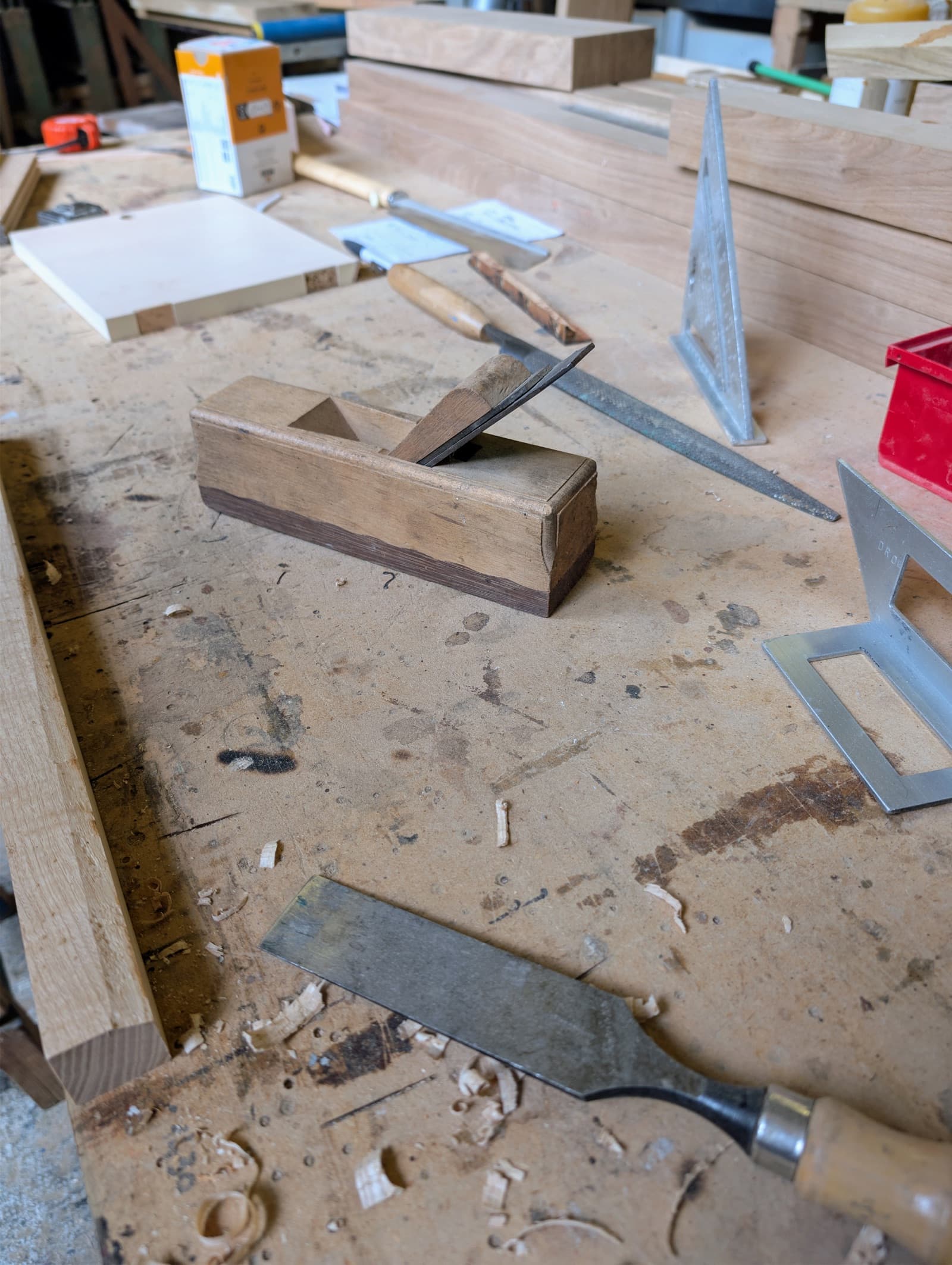 Rabot en bois ancien, équerre et ciseau à bois posés sur l'établi